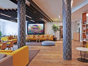 Un intérieur moderne avec un canapé jaune, des chaises en bois, un grand écran de télévision et un plancher en bois.