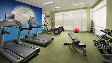 A gym with treadmills, elliptical machines, a bench, and dumbbells.