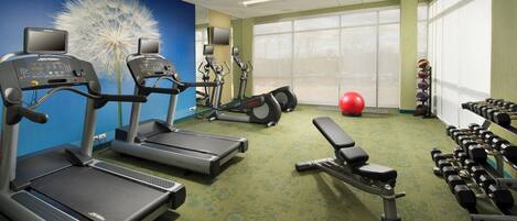 A gym with treadmills, elliptical machines, a bench, and dumbbells.