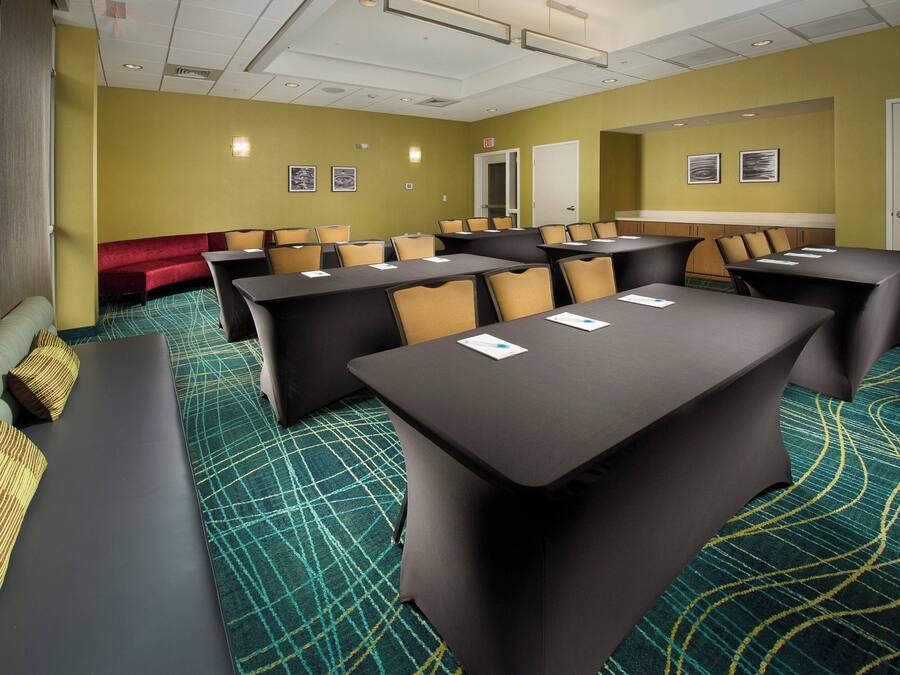 A conference room with tables and chairs, a red sofa, and patterned carpet.