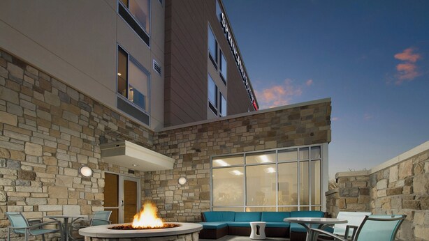 A stone-walled outdoor seating area with a fire feature, a large window, and a stone facade. - SpringHill Suites Bridgeport Clarksburg (Bridgeport)