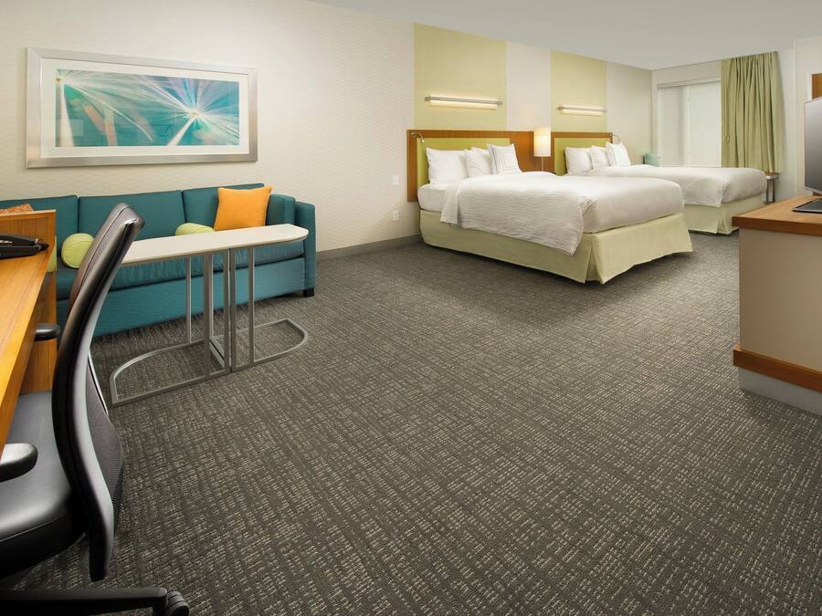 Una habitación de hotel con cama, escritorio con silla, sofá y televisor.