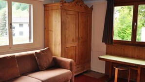 Een kamer met een houten garderobe, een bruine bank en een klein tafeltje.