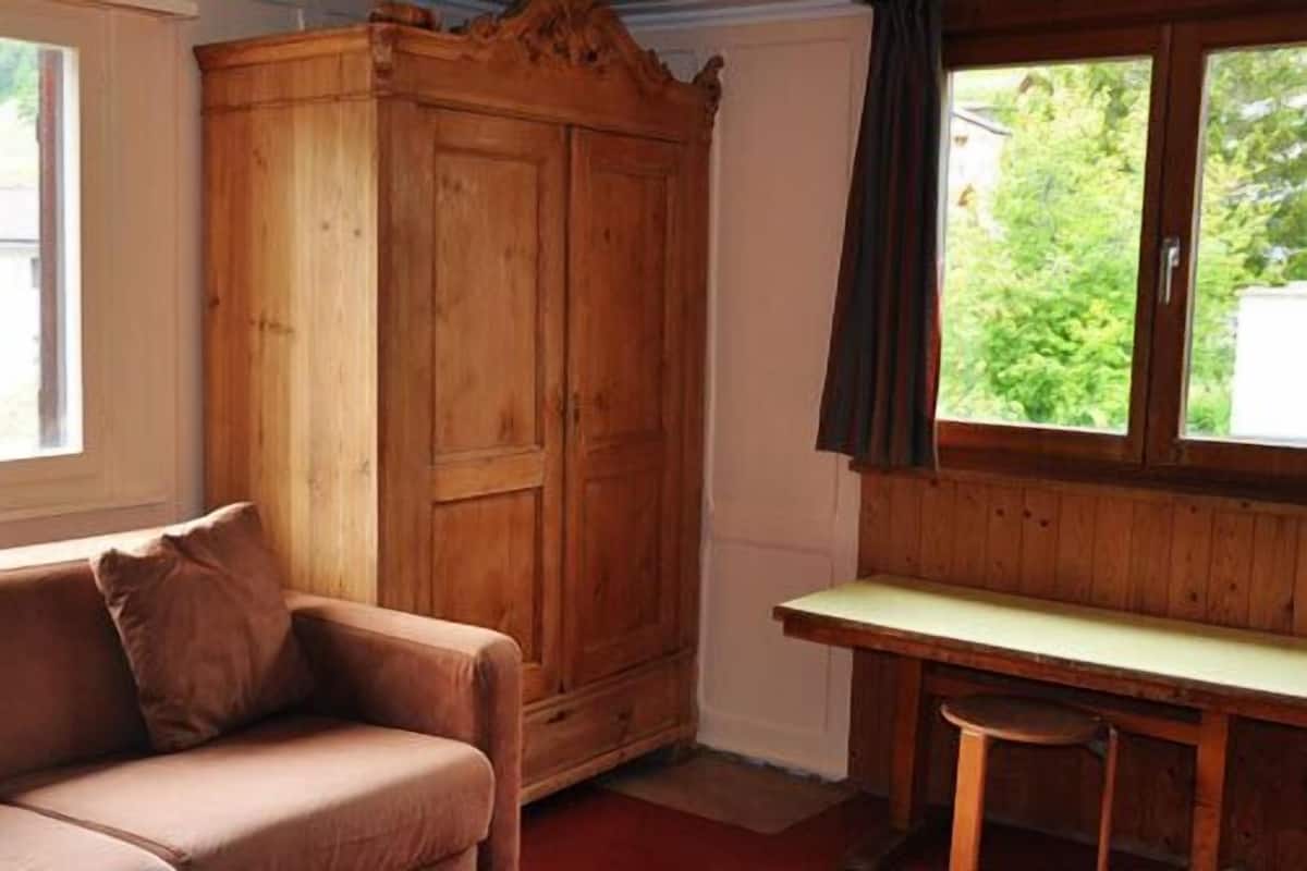 Een kamer met een houten garderobe, een bruine bank en een klein tafeltje.