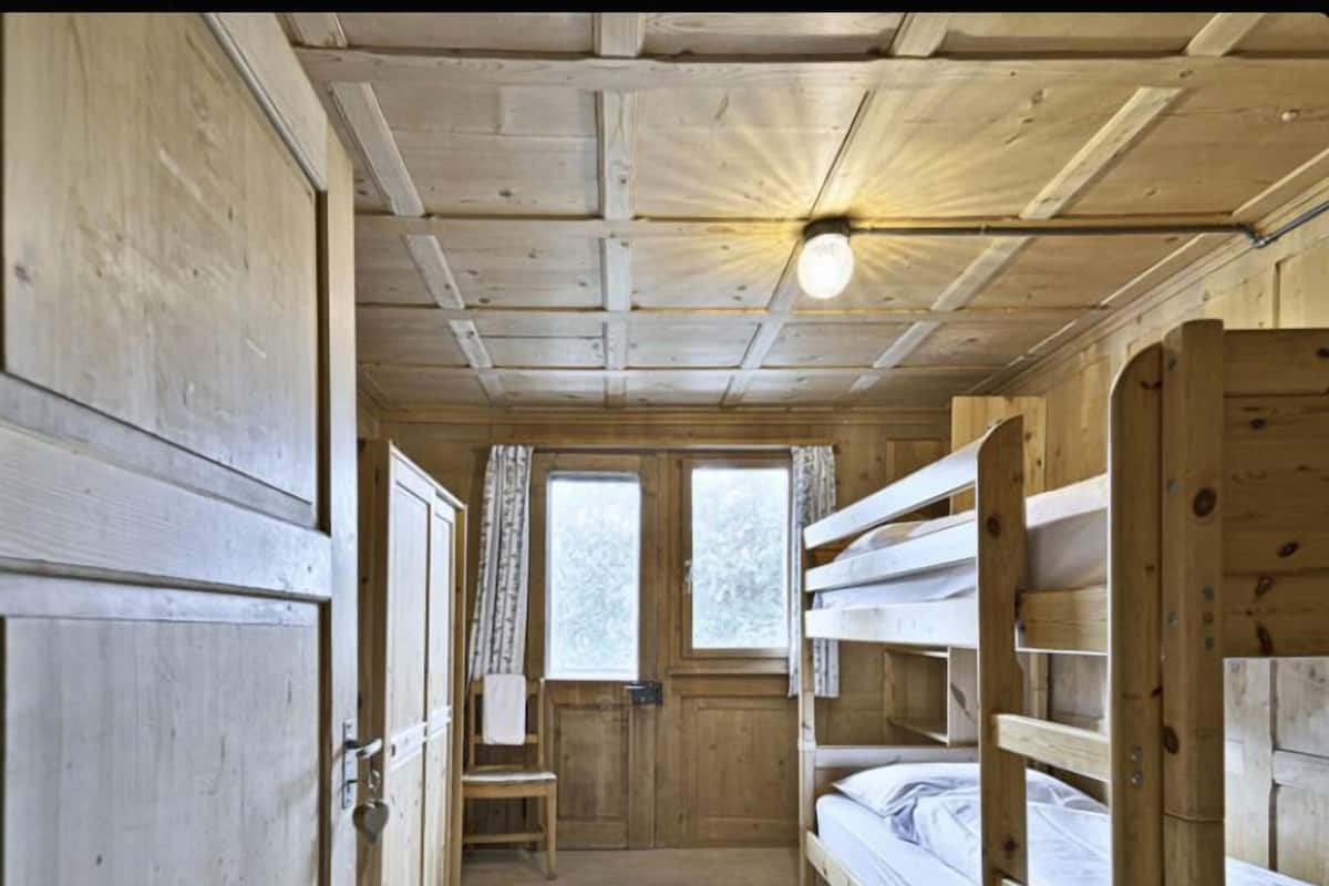 Een houten kamer met stapelbedden, een raam en een deur.