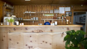 Een houten bar met flessen en glaswerk op planken.