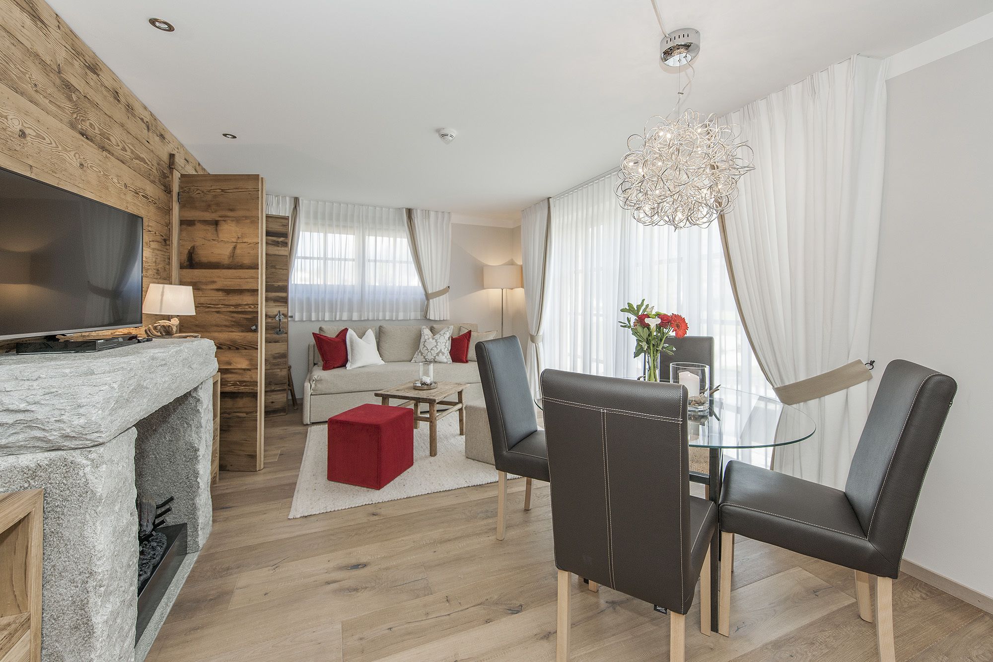 A modern living room with a fireplace, a sofa, a dining area with chairs, and a TV.