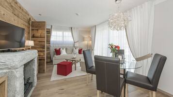 A modern living room with a fireplace, a sofa, a dining area with chairs, and a TV.