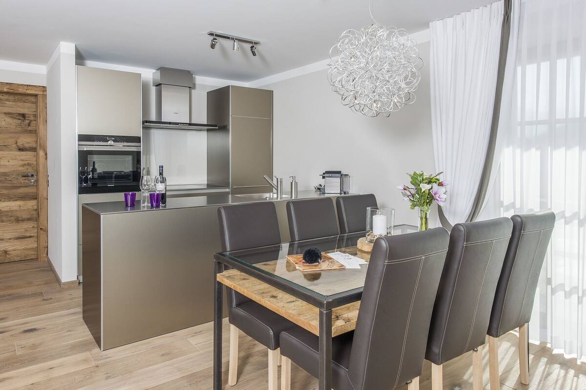 Una cocina moderna con una isla central, electrodomésticos de acero inoxidable y una lámpara colgante.