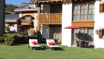 A hotel with a balcony, outdoor seating, and a well-maintained lawn.