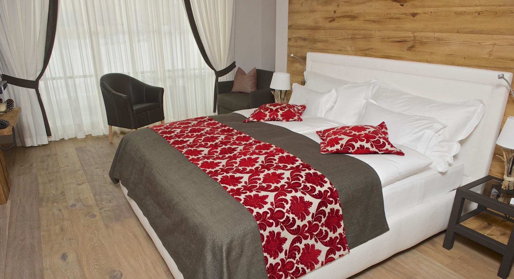 A hotel room with a bed, a chair, a nightstand, and a wooden wall.