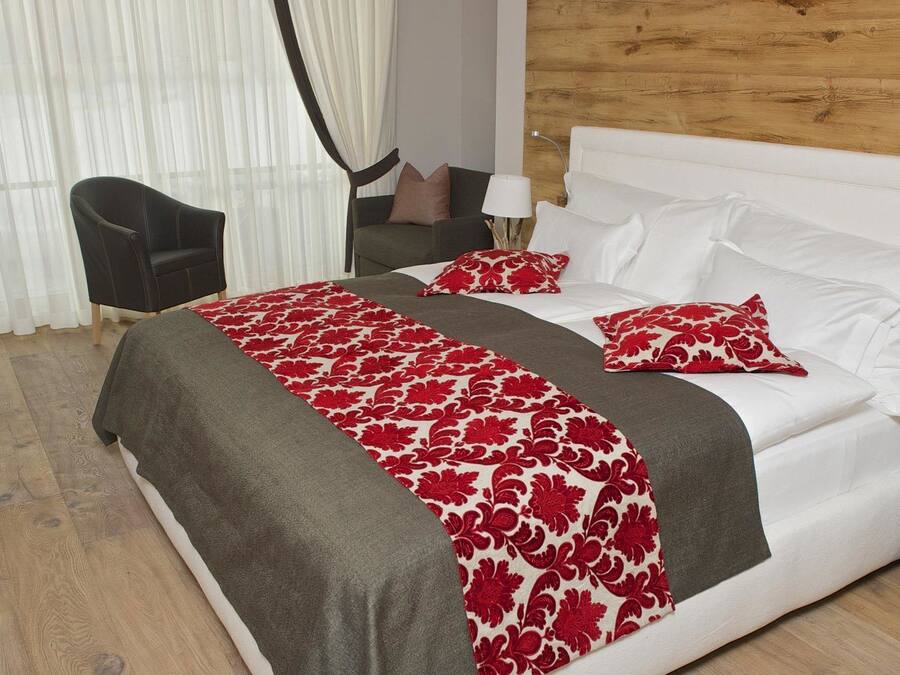 A hotel room with a bed, a chair, a nightstand, and a wooden wall.