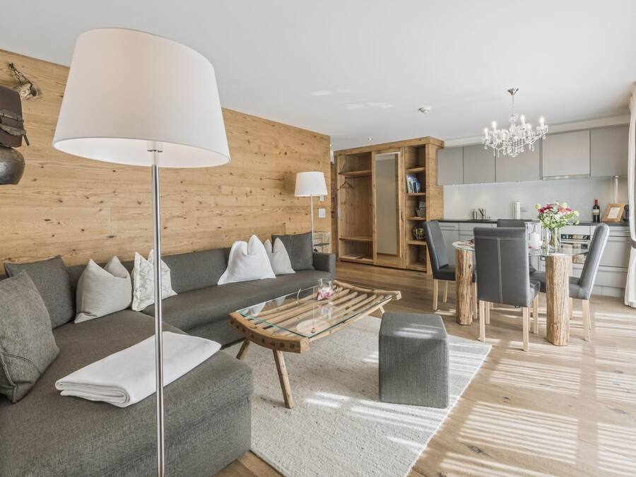 A modern living room with a grey sofa, a glass coffee table, and a wooden floor.