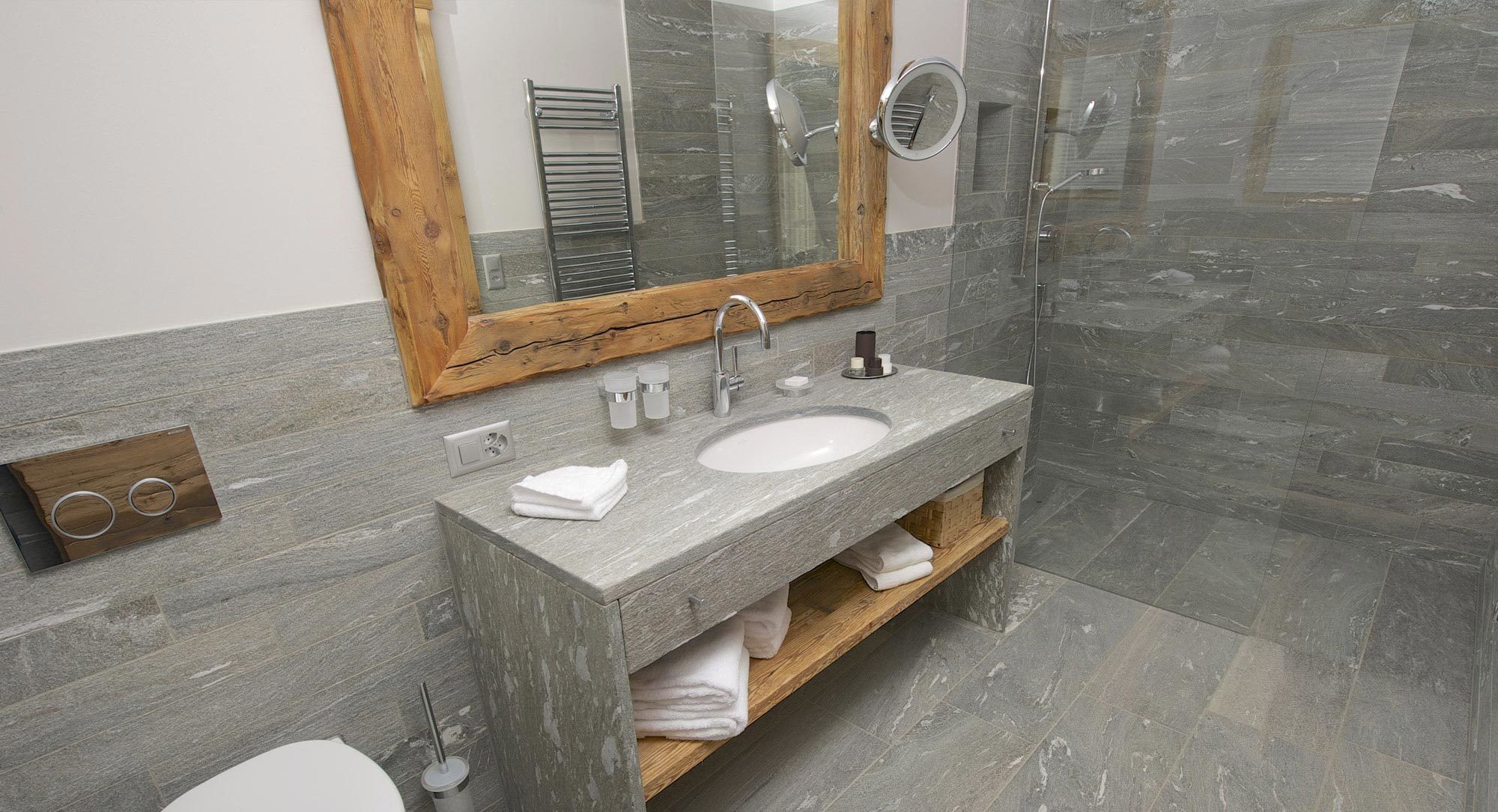 A bathroom with a stone sink, wooden vanity, and a glass shower enclosure.