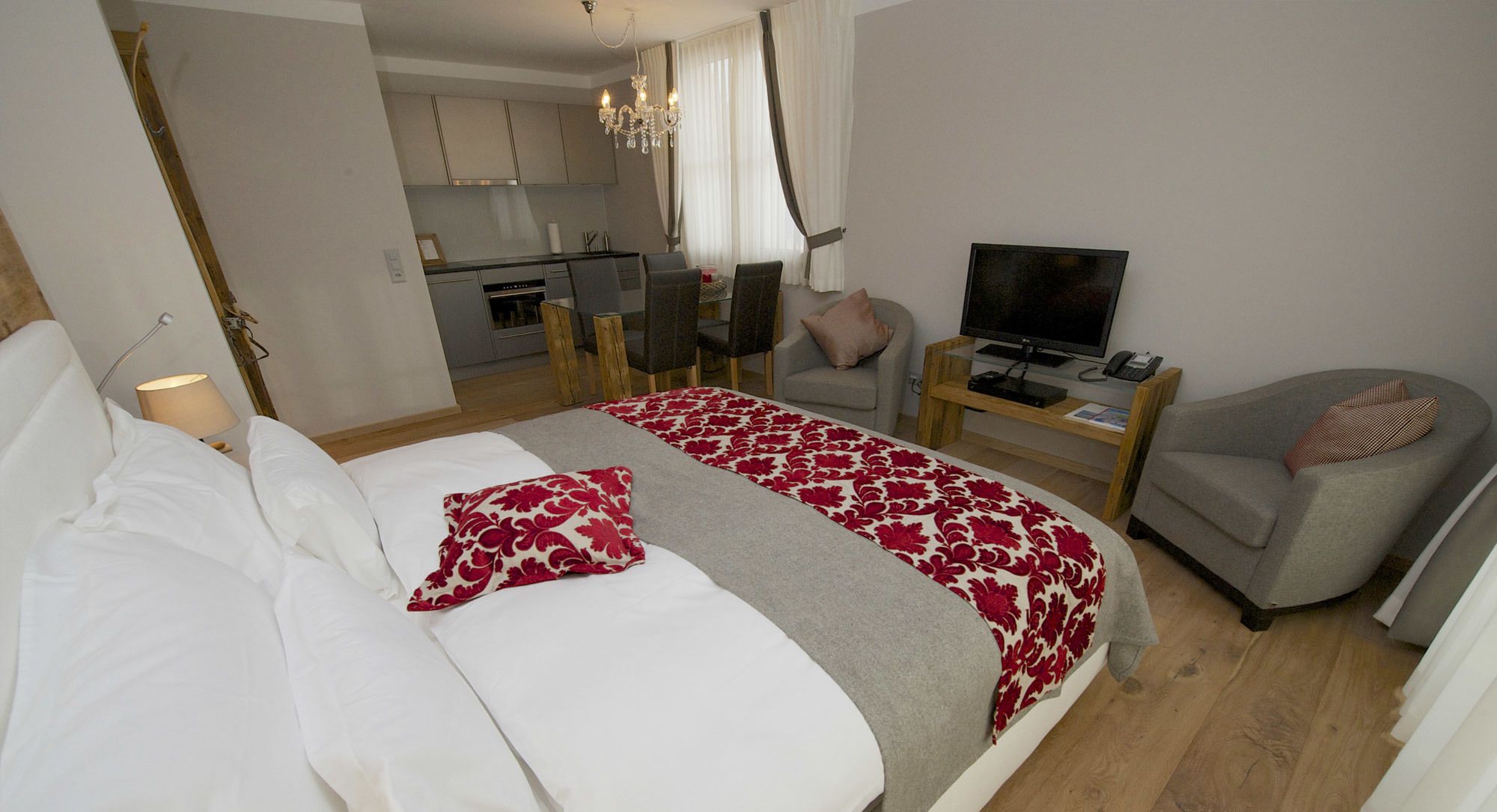 A hotel room with a bed, a TV, a desk, and a chair.