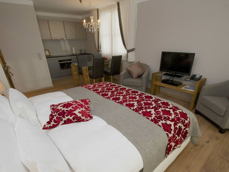 A hotel room with a bed, a TV, a desk, and a chair.