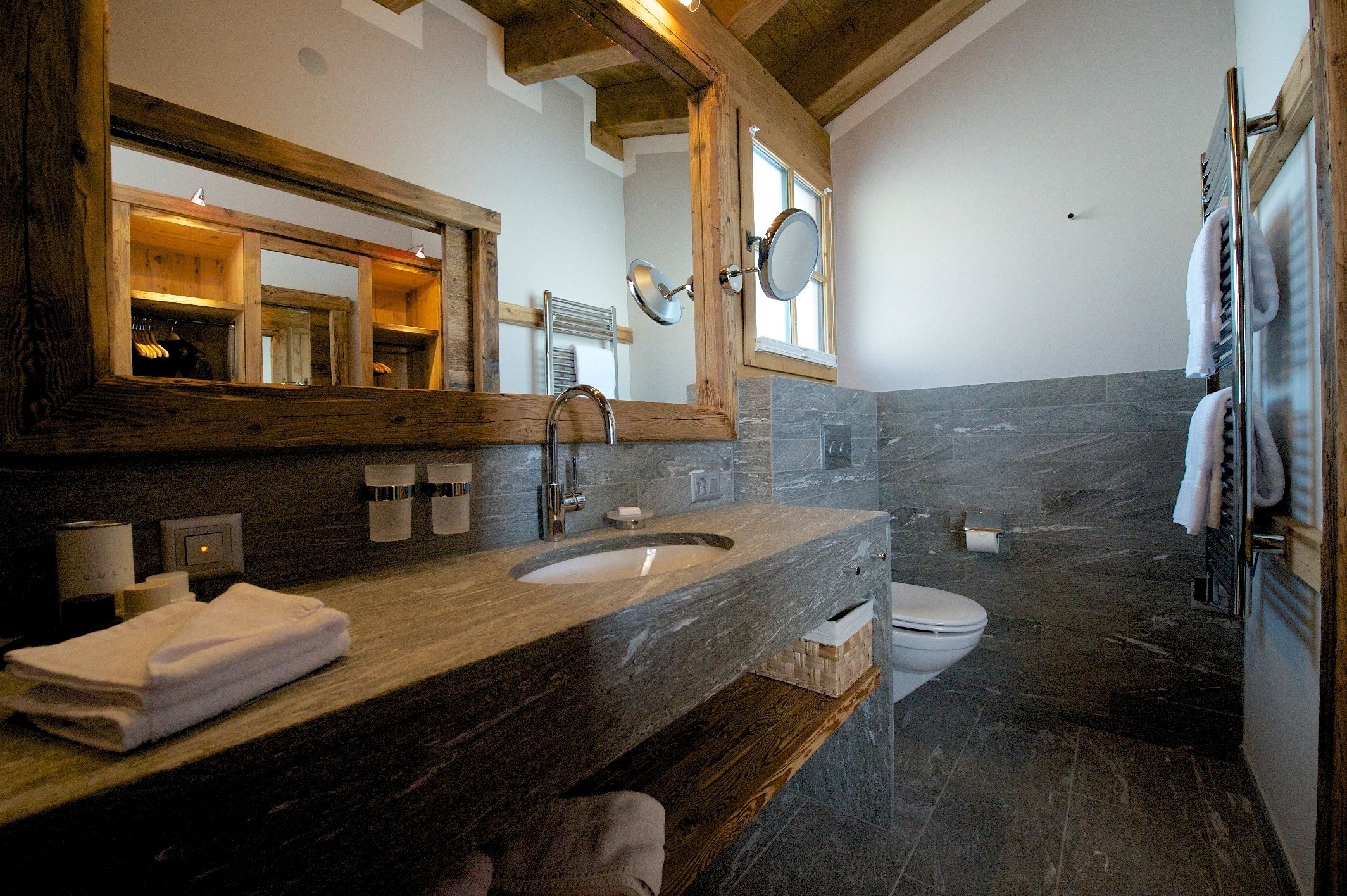 A bathroom with a wooden vanity, a large mirror, a sink, a toilet, and a shower area.