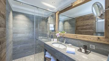 A modern bathroom with a glass shower enclosure, a wooden vanity with a sink, and a large mirror.