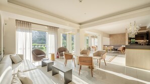 A spacious living area with a sofa, coffee table, and chairs. There is a kitchen area with a dining table and chairs. - Corfu Mare Hotel (Corfu)