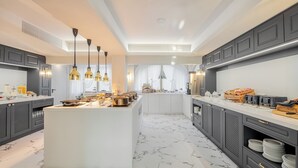 A modern kitchen with a central island, dark cabinetry, and marble flooring. - Corfu Mare Hotel (Corfu)