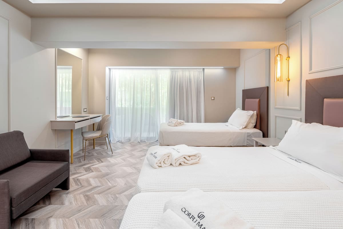 A hotel room with two beds, a desk, a chair, and a sofa.