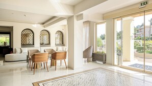 A modern hotel lobby with a seating area, large windows, and a view of the outdoors. - Corfu Mare Hotel (Corfu)