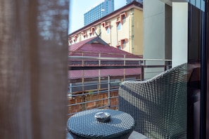 A balcony with a wicker chair and a small round table.