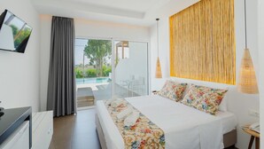 A modern hotel room with a bed, a TV, a desk, and a view of a pool. - Belmare Hotel (Rhodes)