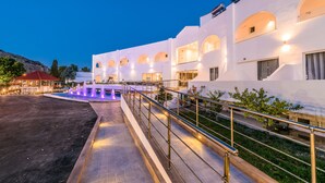 A modern hotel with a pool, outdoor seating, and a well-lit entrance. - Belmare Hotel (Rhodes)