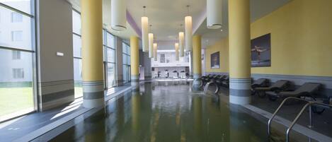 A swimming pool with a clear view of the pool area, including the poolside chairs and the interior design.