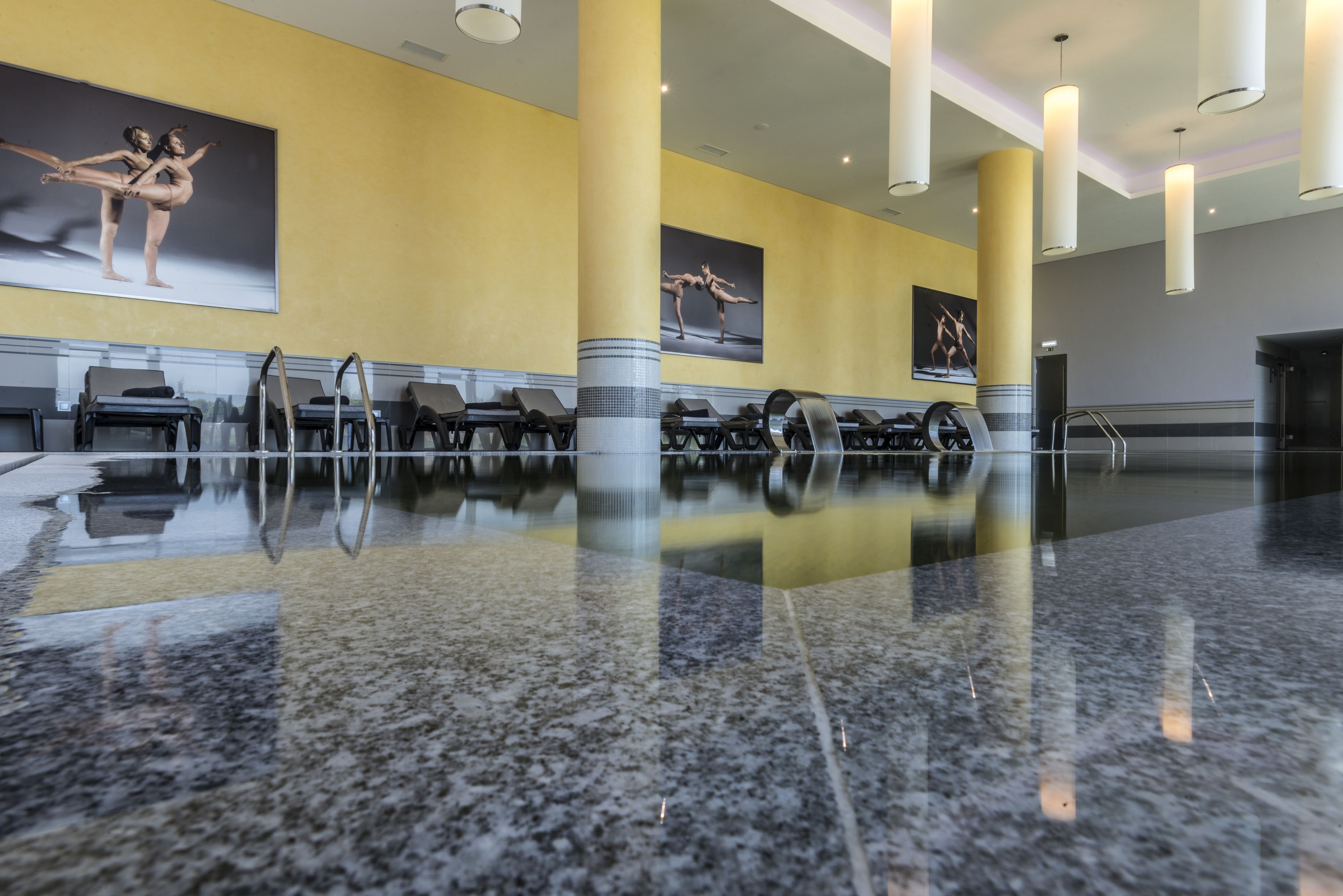 A spacious lobby with a polished marble floor, a row of black chairs, and large columns.