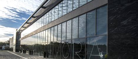 A modern building with large glass windows reflecting the sky.