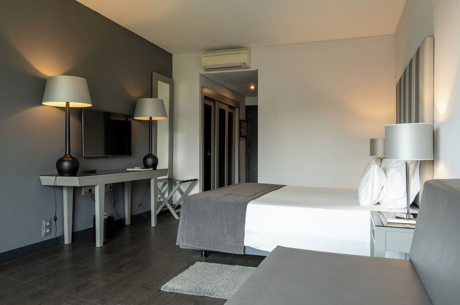 Una habitación de hotel moderna con cama, escritorio y dos lámparas.