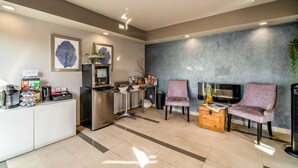 A reception area with a counter, coffee machine, seating, and a TV.