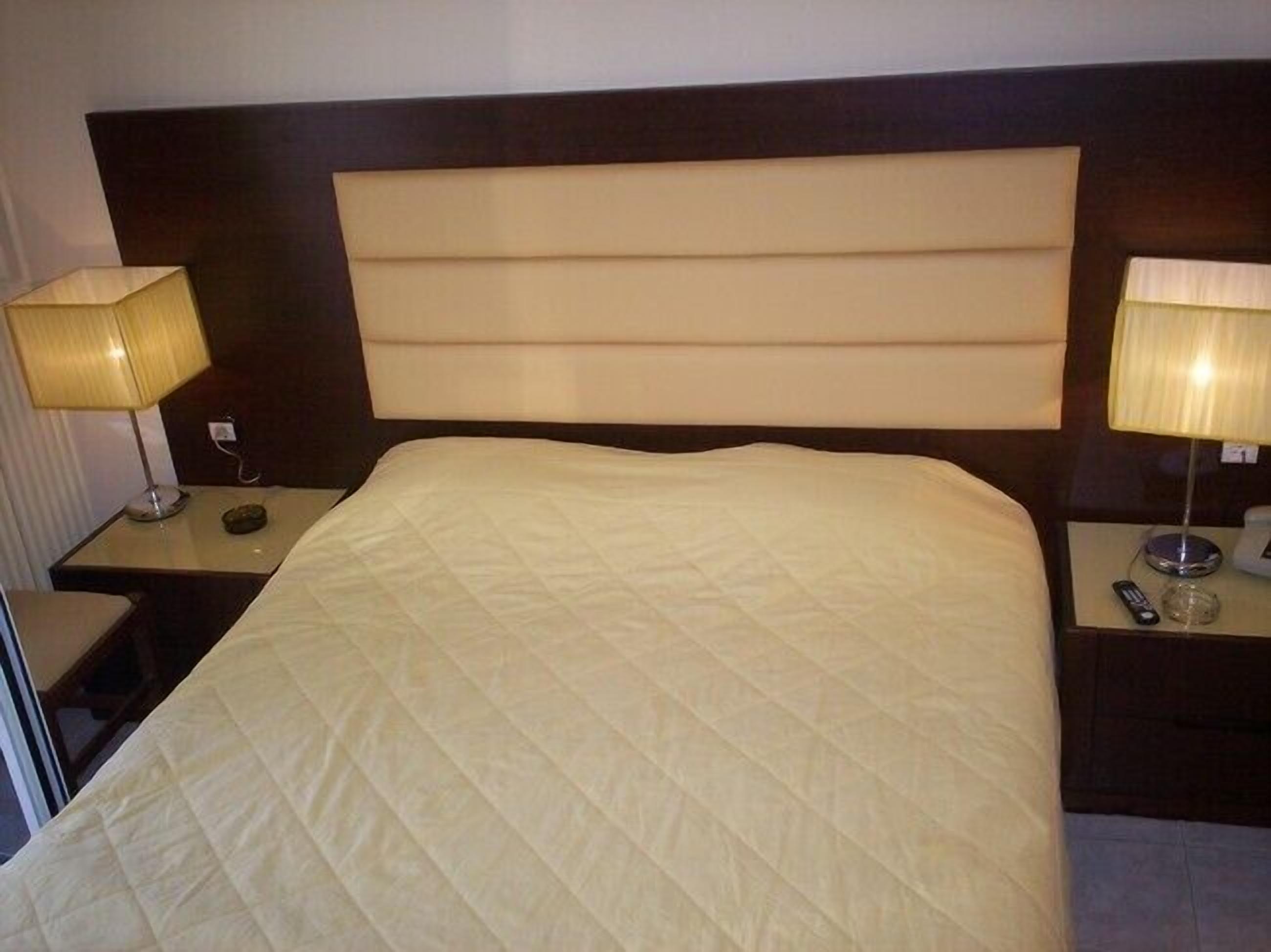 A hotel room with a large bed, two bedside tables, and lamps.