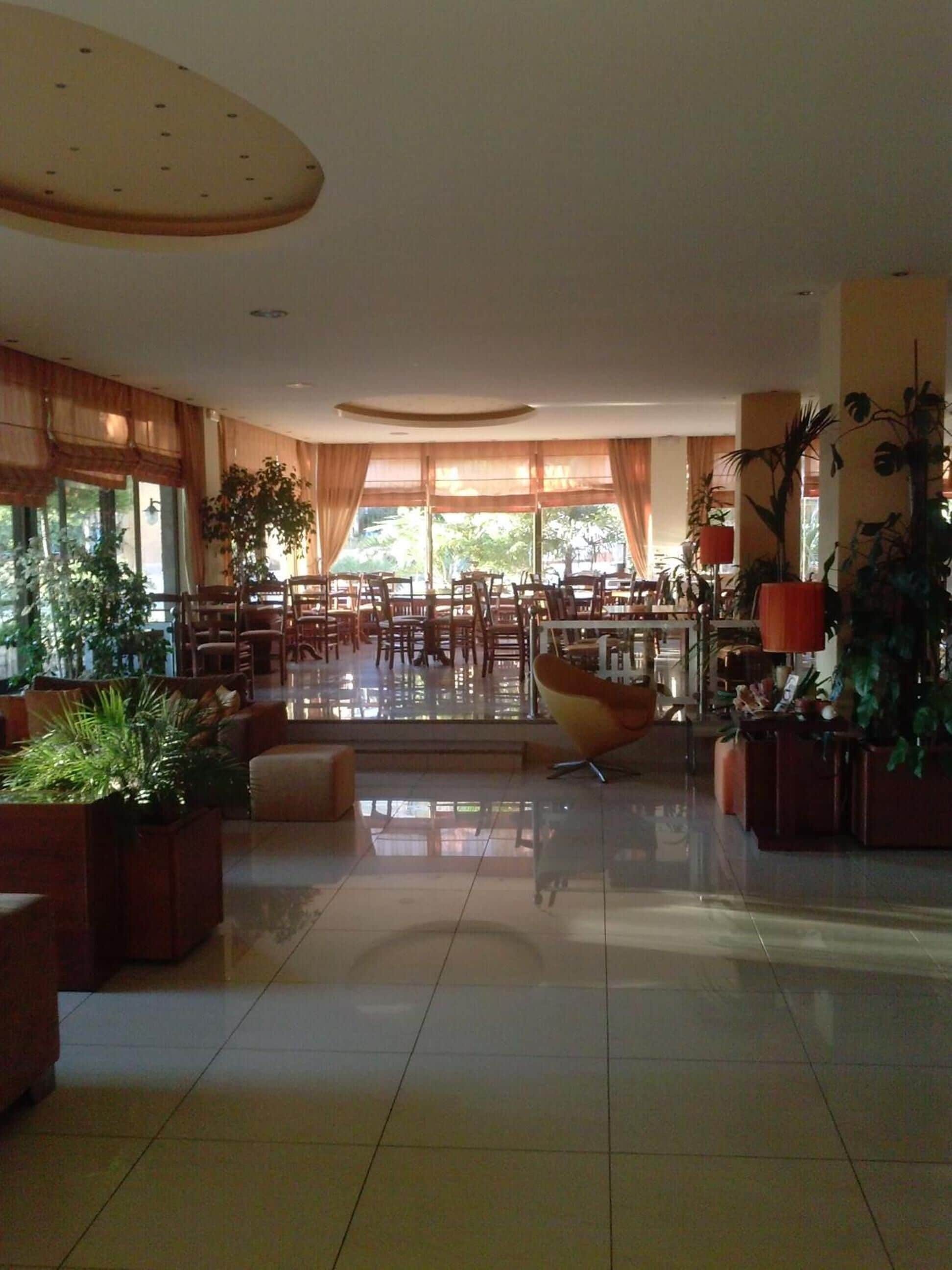 A spacious lobby with a central seating area, large windows, and potted plants.