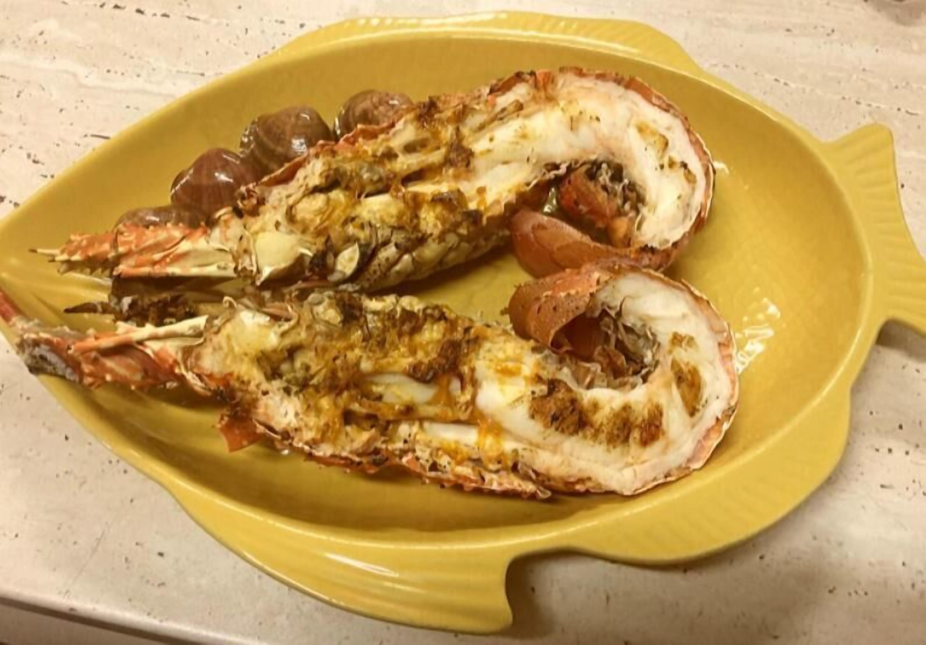 A yellow plate with two cooked lobsters.