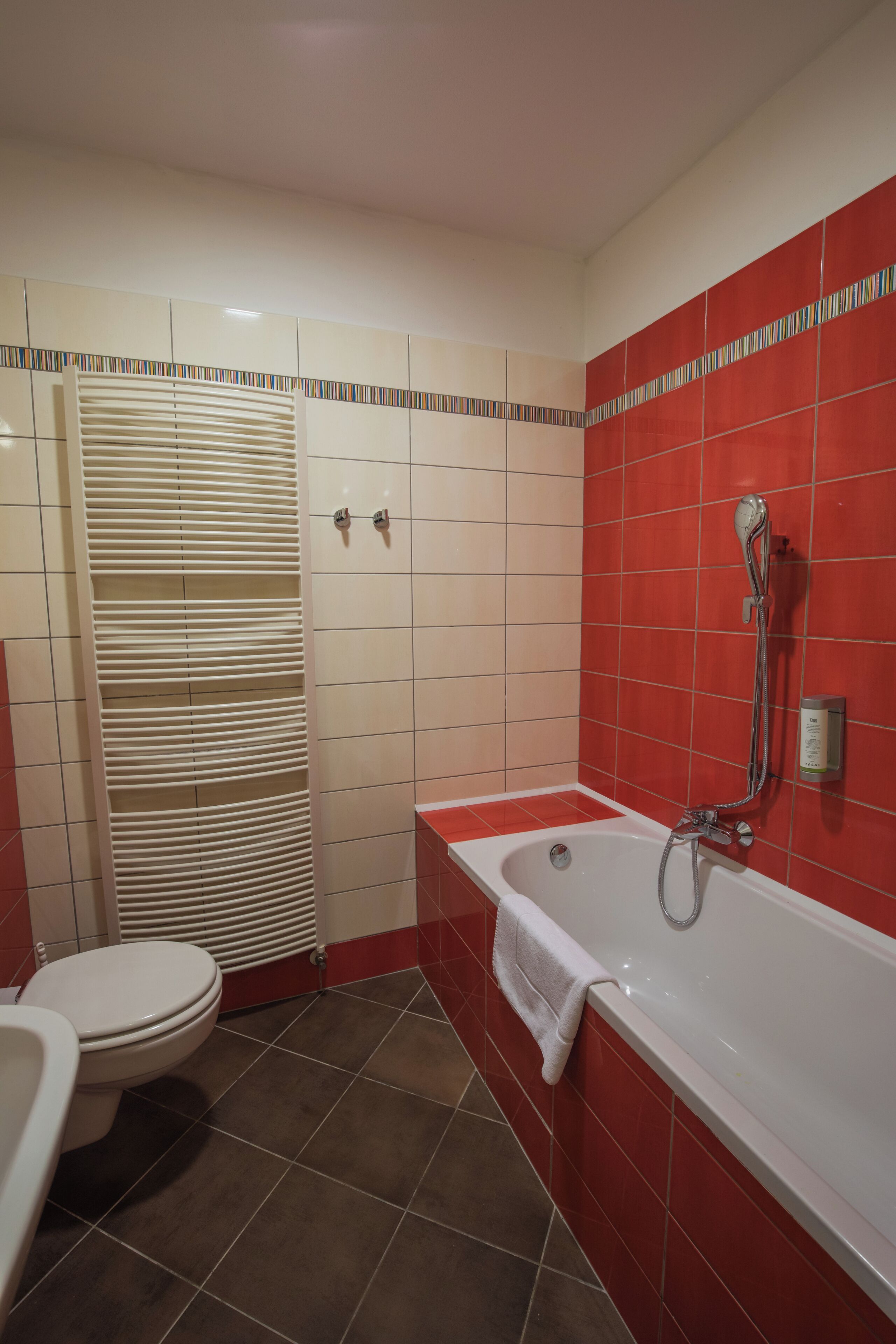 A bathroom with a white bathtub, a toilet, and a shower area.