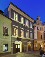 Un edificio histórico con un letrero que indica Hotel Alchymy Riverside, que presenta una fachada tradicional con múltiples ventanas y una entrada en esquina.