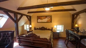 A bedroom with a large bed, wooden beams, a chandelier, a desk, and a chair. - Depandance Edward Kelly (Cesky Krumlov)
