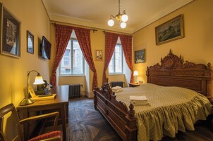 Un dormitorio tradicional con una cama de madera, un escritorio con lámpara y un radiador.