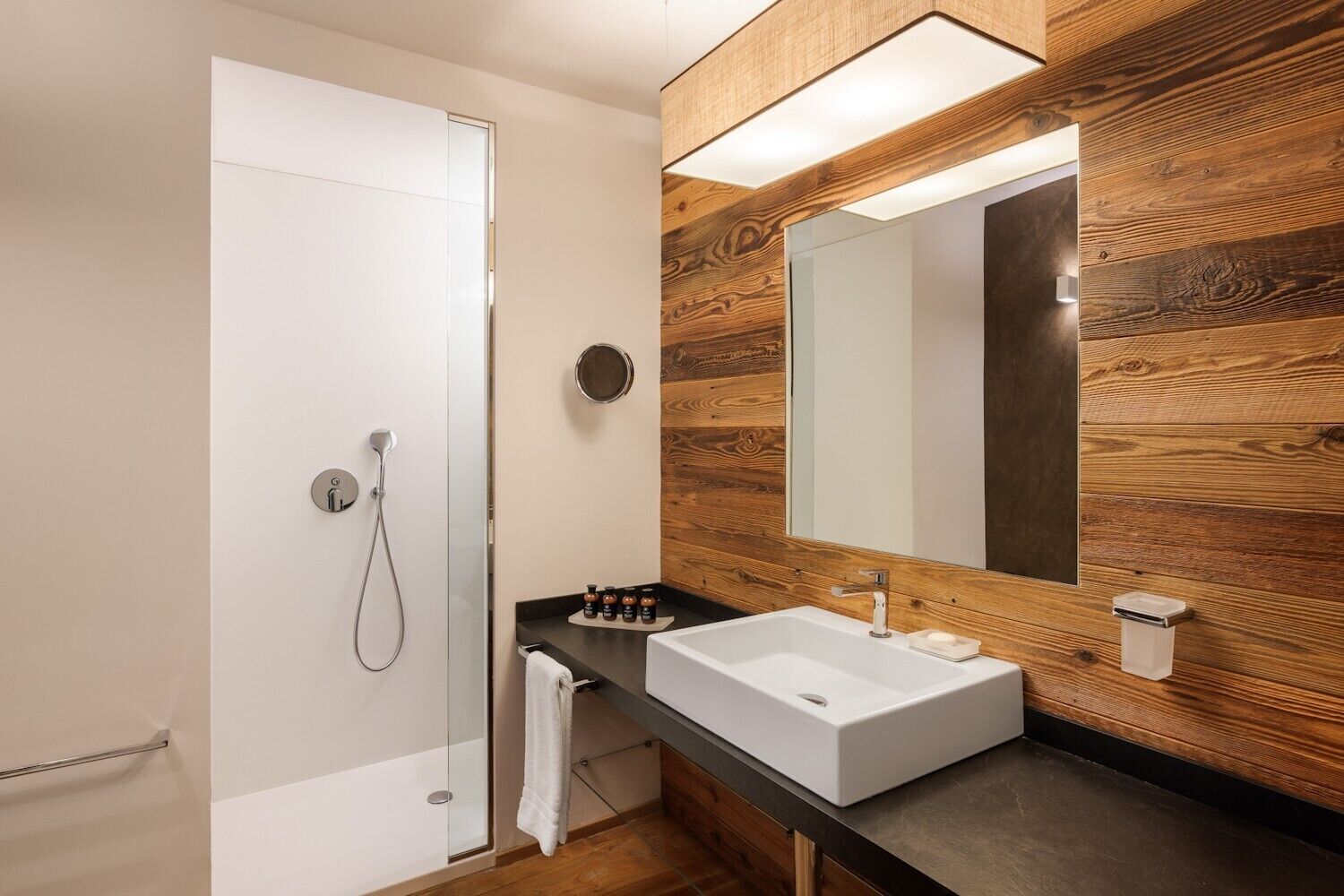 Une salle de bain moderne avec une douche à parois de verre, un lavabo blanc et un meuble-lavabo en bois.