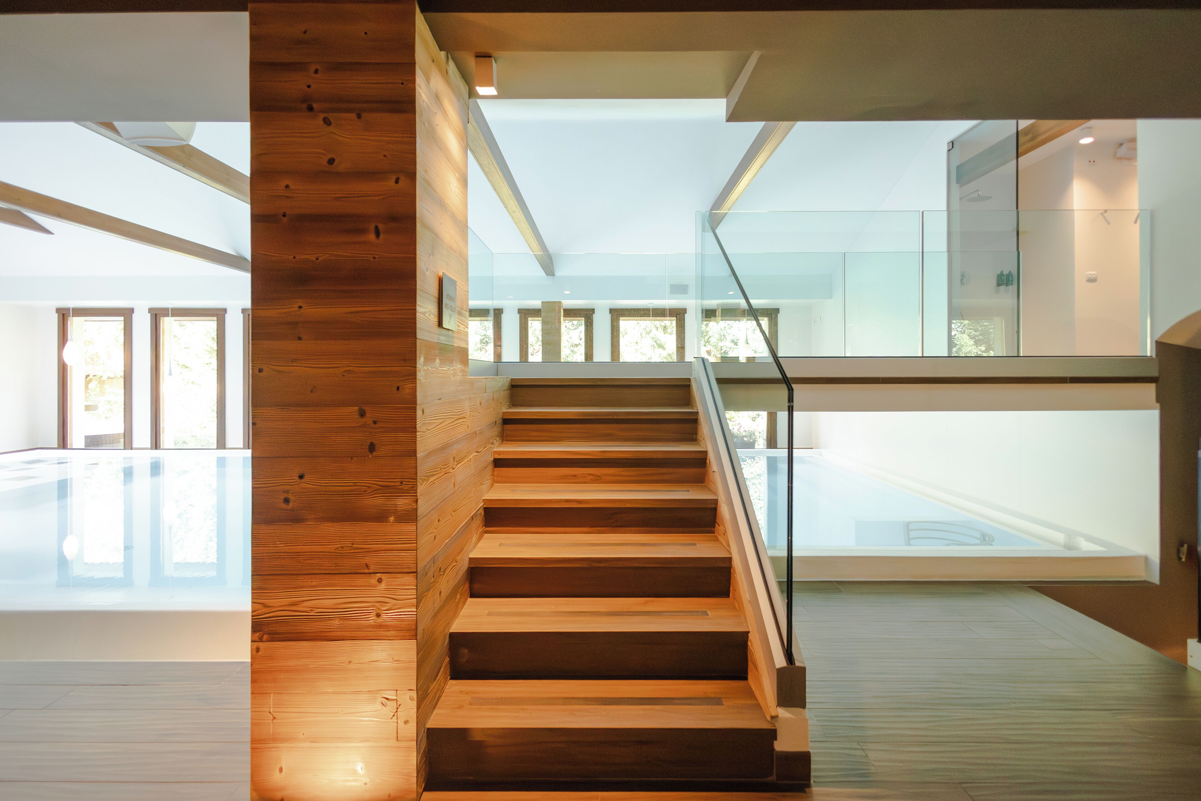 Un intérieur moderne avec un escalier en bois menant à une rambarde en verre.