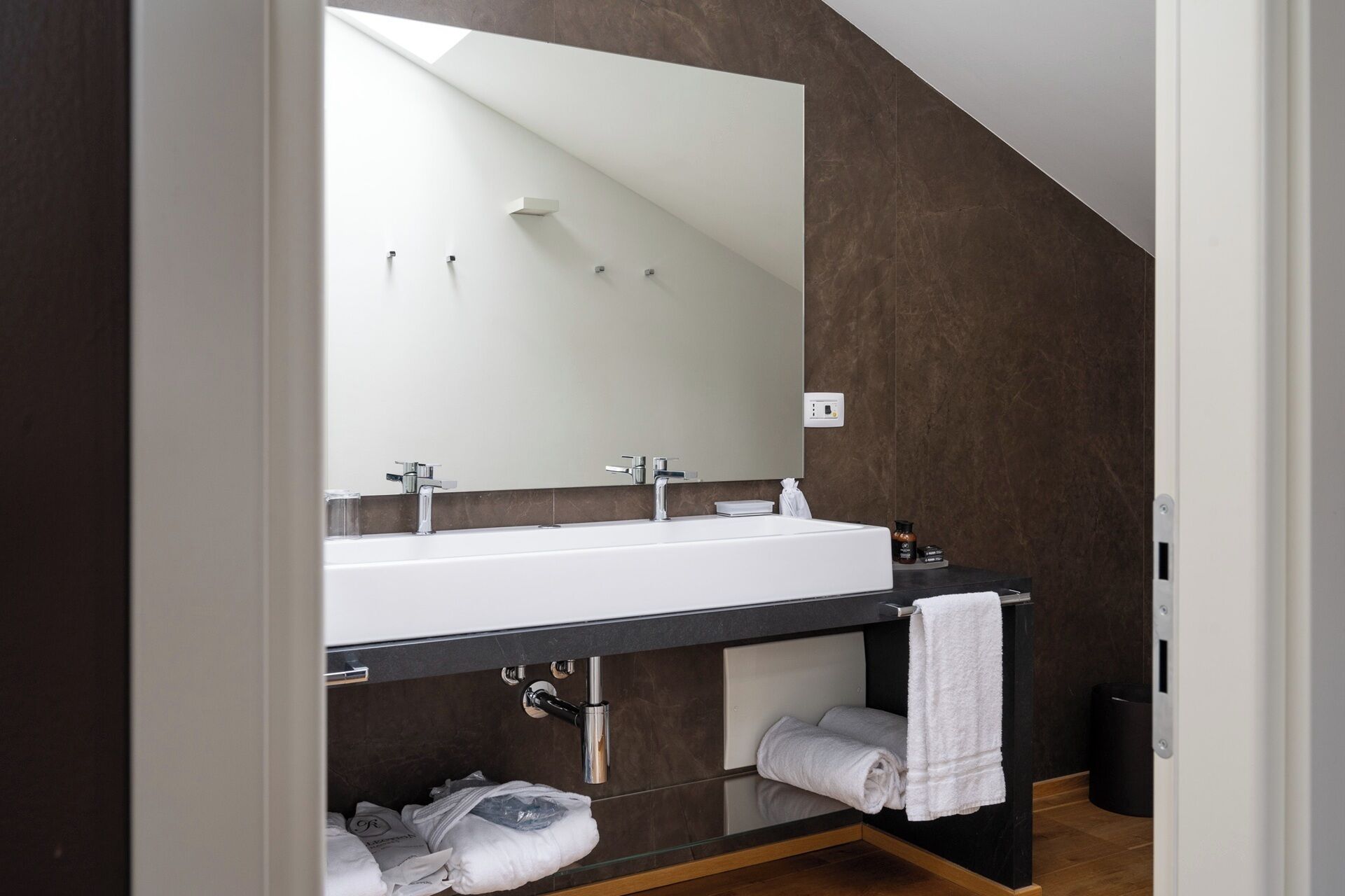 A modern bathroom with a large mirror, a white sink, and a towel rack.