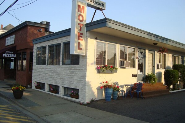 Un motel con fachada blanca, ventanas amplias y un letrero.