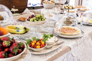 A buffet table with various food items including fruits, cheeses, and pastries. - Giardino della Pieve Relais (Cascina)