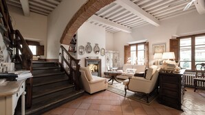 Amplia sala de estar con chimenea, una escalera y vistas al exterior.