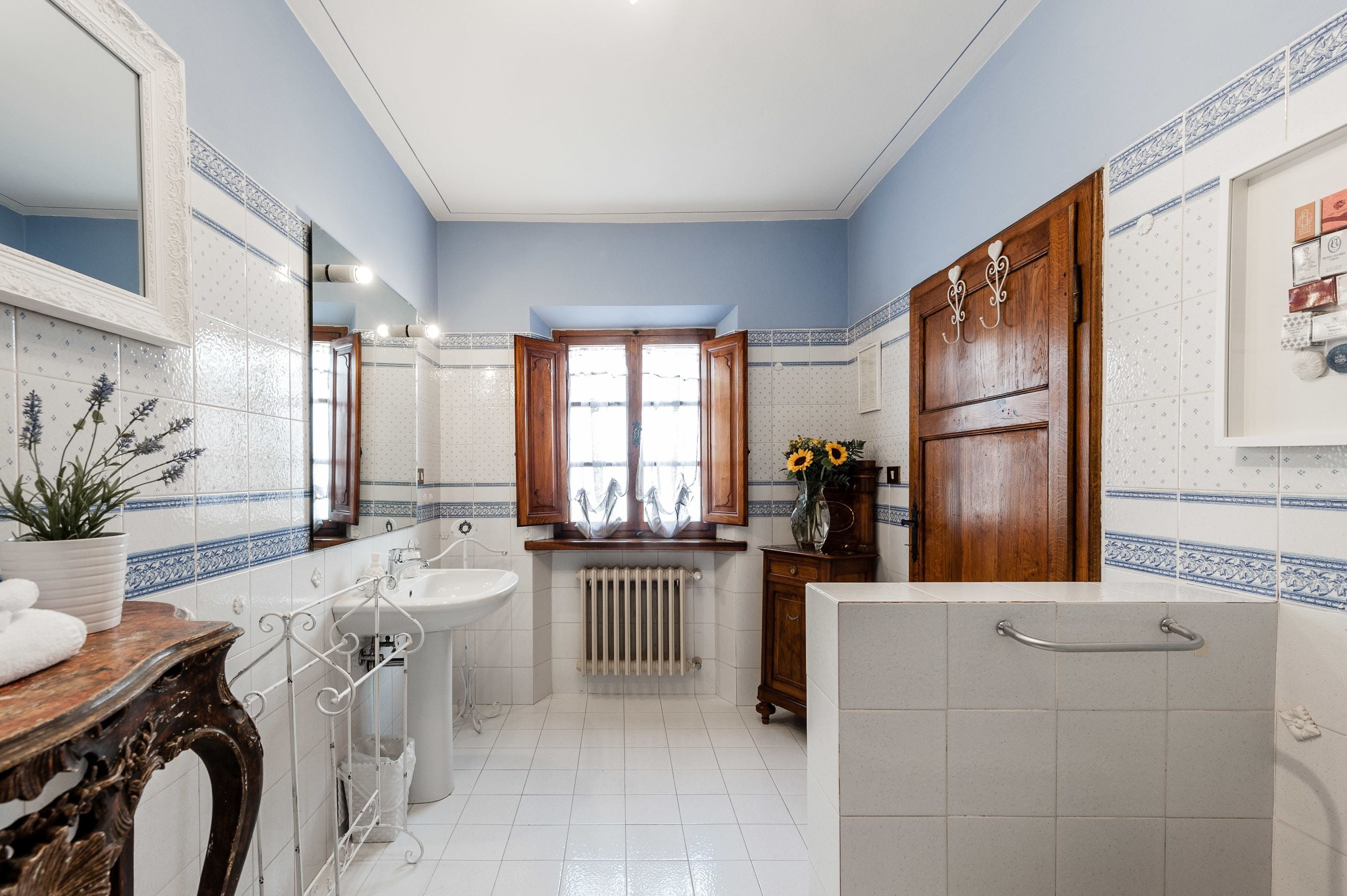 Une salle de bain avec un lavabo blanc, un miroir, un meuble-lavabo en bois, un radiateur et un espace douche.