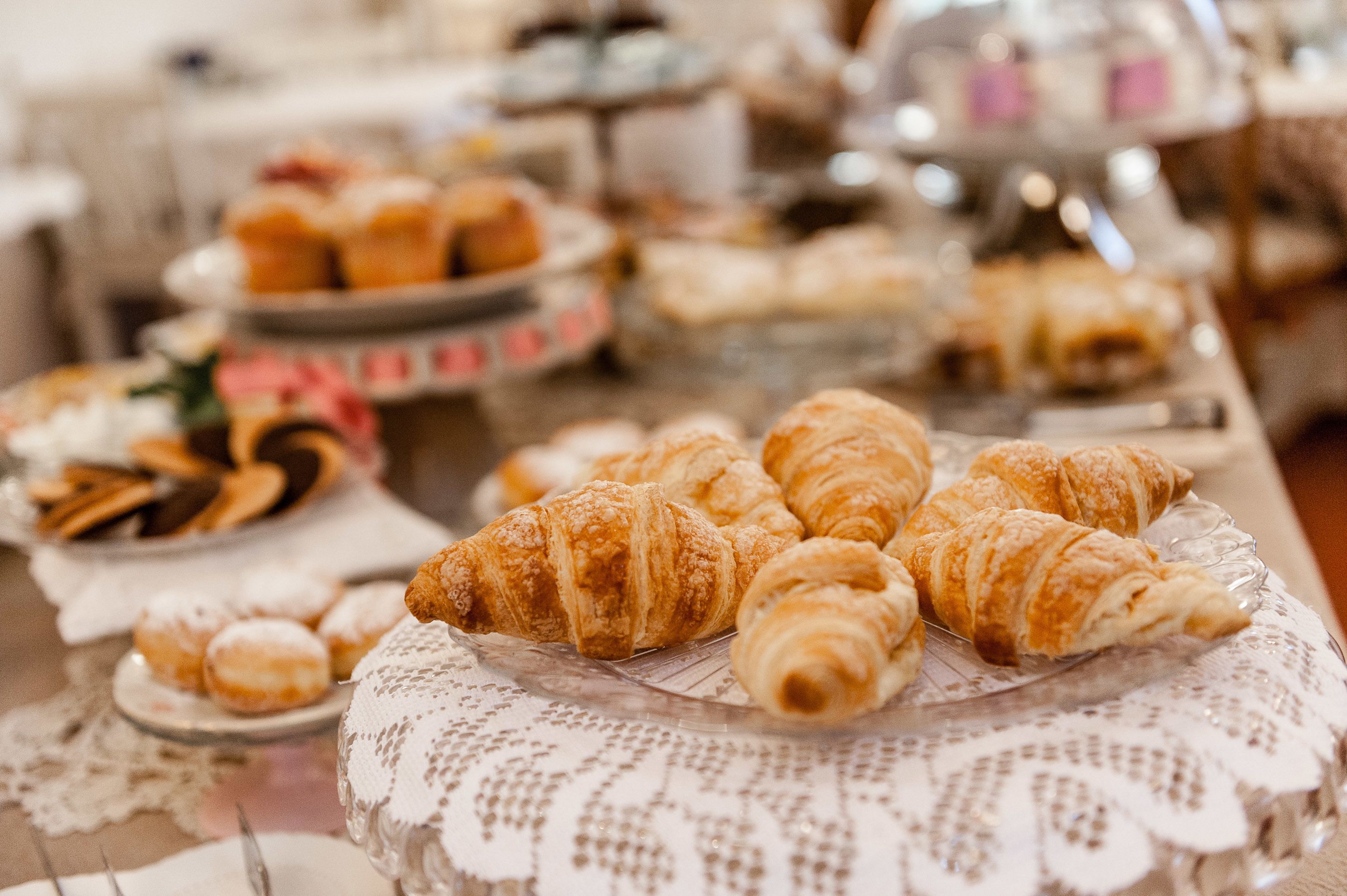 Una mesa con diversos pasteles y productos de panadería, incluyendo cruasanes y donas.