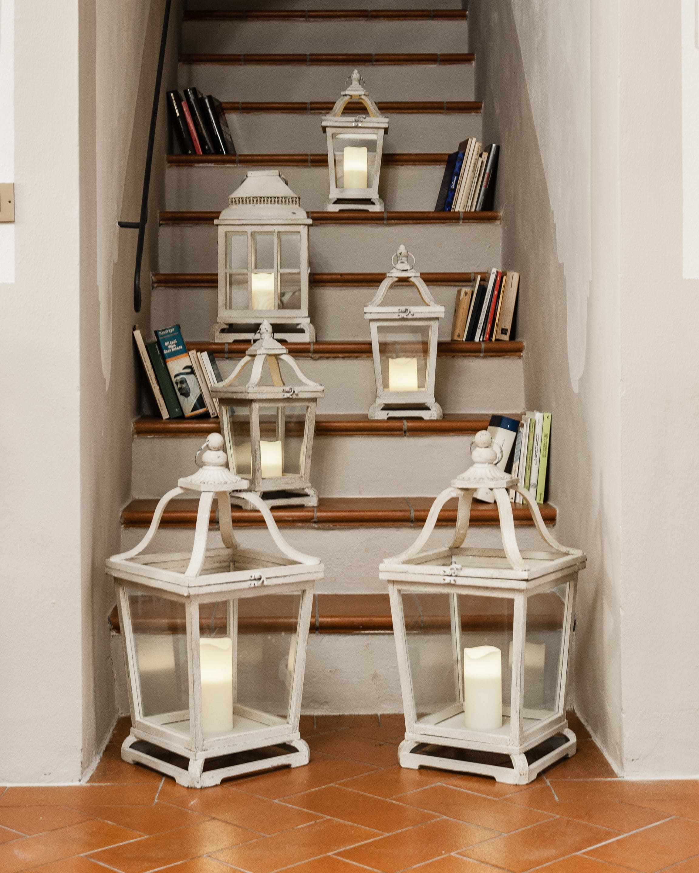 Eine Treppe mit weißen Laternen und Bücherregalen.